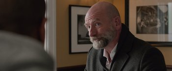 Movie still from “Creed” (2015), directed by Ryan Coogler – A man with a beard and a suit and tie; Close Up shot, Over the shoulder angle