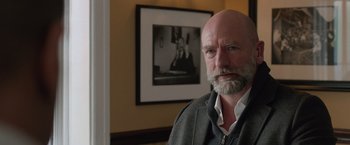 Movie still from “Creed” (2015), directed by Ryan Coogler – An older man with a beard standing in front of a picture; Close Up shot, Over the shoulder angle