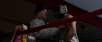 Movie still from “Creed” (2015), directed by Ryan Coogler – Two men in a boxing ring one of whom is wearing a boxing helmet; Medium shot, Over the shoulder angle