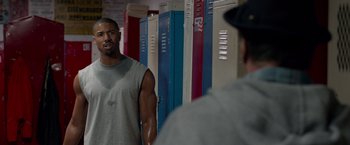 Movie still from “Creed” (2015), directed by Ryan Coogler – A man standing in front of a row of lockers; Medium shot, Over the shoulder angle