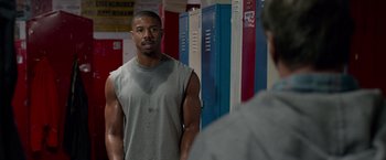 Movie still from “Creed” (2015), directed by Ryan Coogler – A man standing in front of a mirror in a gym; Medium shot, Over the shoulder angle