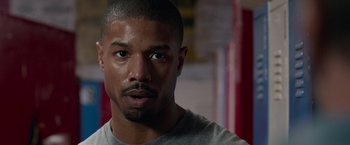 Movie still from “Creed” (2015), directed by Ryan Coogler – A person wearing a gray t - shirt; Close Up shot, Over the shoulder angle
