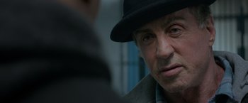 Movie still from “Creed” (2015), directed by Ryan Coogler – A person wearing a hat; Close Up shot, Over the shoulder angle