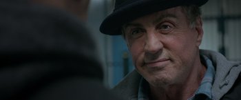 Movie still from “Creed” (2015), directed by Ryan Coogler – An older man wearing a black hat looking at the camera; Close Up shot, Over the shoulder angle