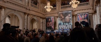 Movie still from “Creed” (2015), directed by Ryan Coogler – A crowd of people in a large room with posters; Wide shot, High angle