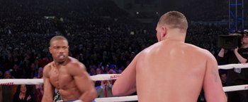 Movie still from “Creed” (2015), directed by Ryan Coogler – A man standing in the middle of a boxing ring; Medium shot, Over the shoulder angle