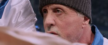 Movie still from “Creed” (2015), directed by Ryan Coogler – A person wearing a hat and looking to the side; Close Up shot, Over the shoulder angle