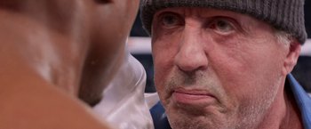 Movie still from “Creed” (2015), directed by Ryan Coogler – An older man wearing a hat looking at the camera; Close Up shot, Over the shoulder angle