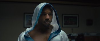 Movie still from “Creed II” (2018), directed by Steven Caple Jr. – A person with a hood on; Close Up shot, Over the shoulder angle