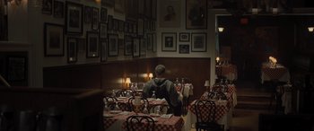 Movie still from “Creed II” (2018), directed by Steven Caple Jr. – A person sitting at a table in a restaurant; Wide shot, High angle