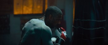 Movie still from “Creed II” (2018), directed by Steven Caple Jr. – A man in a boxing ring getting ready for a fight; Medium shot, Over the shoulder angle