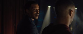 Movie still from “Creed II” (2018), directed by Steven Caple Jr. – A man in a suit is standing in the dark; Close Up shot, Over the shoulder angle