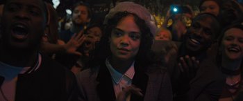 Movie still from “Creed II” (2018), directed by Steven Caple Jr. – A woman in a hat and a suit is in a crowd of people; Close Up shot, Over the shoulder angle