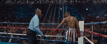 Movie still from “Creed II” (2018), directed by Steven Caple Jr. – Two boxers in a boxing ring facing each other in front of a crowd; Medium shot, Over the shoulder angle