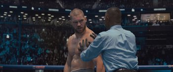 Movie still from “Creed II” (2018), directed by Steven Caple Jr. – A man in a boxing ring getting his hands wrapped; Medium shot, Over the shoulder angle