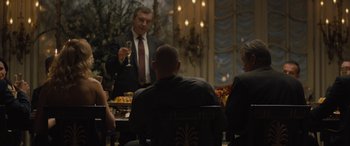 Movie still from “Creed II” (2018), directed by Steven Caple Jr. – A man in a suit and tie holding a glass of wine; Medium shot, Over the shoulder angle