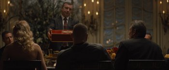 Movie still from “Creed II” (2018), directed by Steven Caple Jr. – A man in a suit and tie holding a box in front of another man; Medium shot, Over the shoulder angle