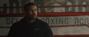 Movie still from “Creed II” (2018), directed by Steven Caple Jr. – A man sitting in front of a boxing ring; Close Up shot, Over the shoulder angle