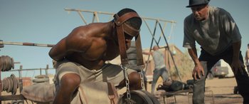 Movie still from “Creed II” (2018), directed by Steven Caple Jr. – A man with a helmet on his head is chained to a swing; Medium shot, Low angle