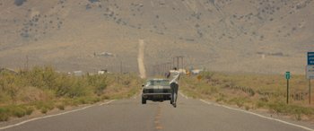 Movie still from “Creed II” (2018), directed by Steven Caple Jr. – A man walking down the street with a car; Wide shot, Low angle
