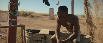 Movie still from “Creed II” (2018), directed by Steven Caple Jr. – A man sitting on top of a metal box; Medium shot, Over the shoulder angle