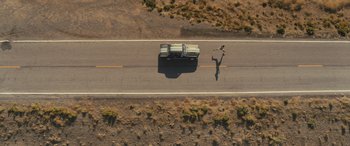 Movie still from “Creed II” (2018), directed by Steven Caple Jr. – An aerial view of a truck on the side of the road with a skateboarder; Extreme Wide shot, Overhead angle