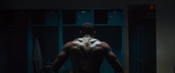 Movie still from “Creed II” (2018), directed by Steven Caple Jr. – A man standing in front of some lockers; Medium shot, Low angle