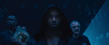 Movie still from “Creed II” (2018), directed by Steven Caple Jr. – A man in a hooded jacket and a man in a black shirt; Close Up shot, Low angle