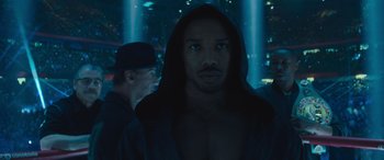 Movie still from “Creed II” (2018), directed by Steven Caple Jr. – A person wearing a hooded jacket; Close Up shot, Low angle