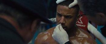 Movie still from “Creed II” (2018), directed by Steven Caple Jr. – A man is getting his nose hair cut by a barber; Close Up shot, Over the shoulder angle