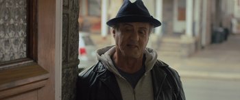 Movie still from “Creed II” (2018), directed by Steven Caple Jr. – A man wearing a hat and a leather jacket; Close Up shot, Over the shoulder angle