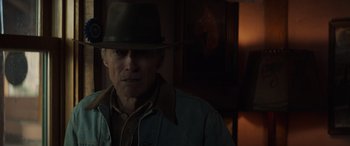 Movie still from “Cry Macho” (2021), directed by Clint Eastwood – An older man wearing a cowboy hat in front of a painting; Close Up shot, Low angle