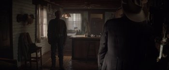 Movie still from “Cry Macho” (2021), directed by Clint Eastwood – Two people standing in a dark room in front of a counter; Wide shot, Over the shoulder angle