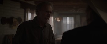 Movie still from “Cry Macho” (2021), directed by Clint Eastwood – An older man standing in a dark room; Close Up shot, Over the shoulder angle