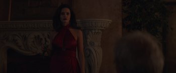Movie still from “Cry Macho” (2021), directed by Clint Eastwood – A woman in a red dress standing next to a pillar; Medium shot, Over the shoulder angle
