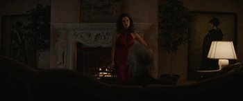 Movie still from “Cry Macho” (2021), directed by Clint Eastwood – A woman in a red dress standing in front of a fireplace; Wide shot, Over the shoulder angle