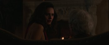 Movie still from “Cry Macho” (2021), directed by Clint Eastwood – A woman sitting in front of a lit candle in the dark; Close Up shot, Over the shoulder angle