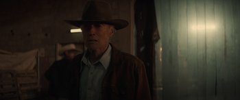 Movie still from “Cry Macho” (2021), directed by Clint Eastwood – An older man wearing a brown hat and a brown jacket; Medium shot, Over the shoulder angle