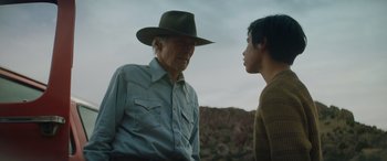 Movie still from “Cry Macho” (2021), directed by Clint Eastwood – An older man and a younger man are standing outside; Medium shot, Over the shoulder angle