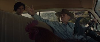 Movie still from “Cry Macho” (2021), directed by Clint Eastwood – An older man in a hat driving a car; Medium shot, Low angle