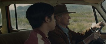 Movie still from “Cry Macho” (2021), directed by Clint Eastwood – A man and a young boy in a car looking out the window; Medium shot, Over the shoulder angle