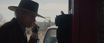 Movie still from “Cry Macho” (2021), directed by Clint Eastwood – A man talking on a cell phone next to a car; Close Up shot, Over the shoulder angle