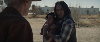 Movie still from “Cry Macho” (2021), directed by Clint Eastwood – A man and a woman holding each other in a field; Close Up shot, Over the shoulder angle