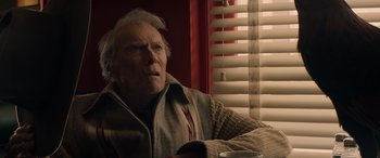 Movie still from “Cry Macho” (2021), directed by Clint Eastwood – An older man sitting in front of a window; Close Up shot, Low angle