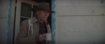 Movie still from “Cry Macho” (2021), directed by Clint Eastwood – An older man holding a cup in his hand; Medium shot, Over the shoulder angle