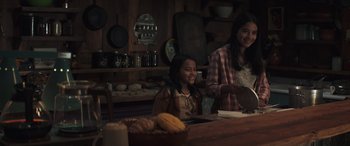 Movie still from “Cry Macho” (2021), directed by Clint Eastwood – Two women are sitting at a table in a kitchen; Medium shot, Over the shoulder angle