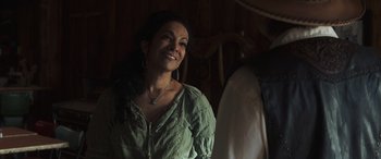 Movie still from “Cry Macho” (2021), directed by Clint Eastwood – A woman in a green shirt smiling for the camera; Close Up shot, Over the shoulder angle