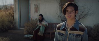 Movie still from “Cry Macho” (2021), directed by Clint Eastwood – A woman sitting on a bench next to another woman; Medium shot, Over the shoulder angle