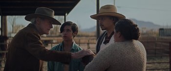 Movie still from “Cry Macho” (2021), directed by Clint Eastwood – A group of people standing around each other in a field; Medium shot, Over the shoulder angle