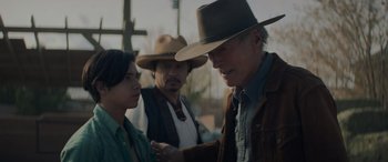 Movie still from “Cry Macho” (2021), directed by Clint Eastwood – A group of people standing next to each other on a field; Medium shot, Over the shoulder angle